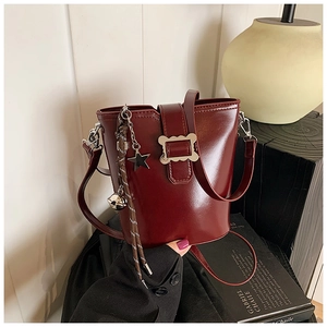 Vue détaillée du sac seau bordeaux avec boucle argentée et charm en forme d'étoile
