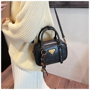 Detail einer Vintage schwarzen Ledertasche mit goldenem Dreieckslogo und geflochtenem Anhänger