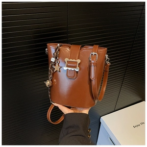 Détail d'un sac seau marron avec boucle en métal et breloque en forme d'étoile