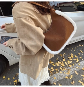 Detail of brown suede shoulder bag with white fluffy trim and golden ginkgo leaf background