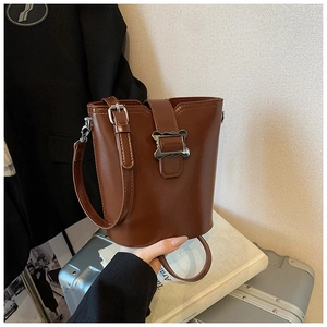 Détail du sac seau marron avec boucle argentée ondulée et bandoulière réglable