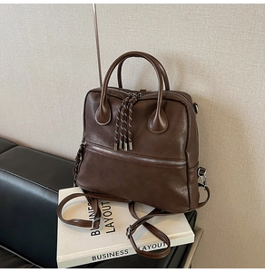 Dettaglio della cartella vintage marrone scuro con trama in pelle e zip con nappe