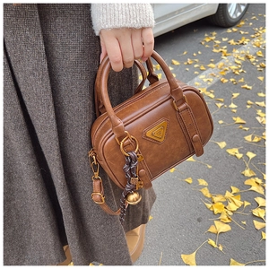 Detail der braunen Vintage-Boston-Tasche mit Öl-Wachs-Textur und Anhänger auf Herbstlaub