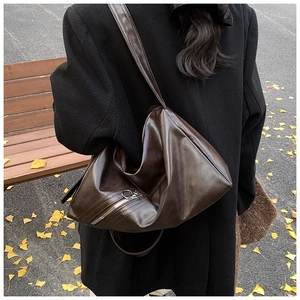 Detail of a large vintage dark brown PU leather hobo bag with zip and ginkgo leaf background