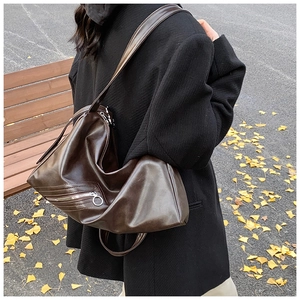 Detail of vintage dark brown hobo bag with metallic zipper and glossy leather texture