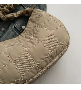 Detail of khaki quilted tote bag with pleated texture and soft fabric on denim background