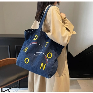 Detail of denim tote bag with yellow 3D embroidery and casual chic shoulder strap