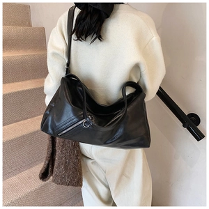 Detail of black leather tote bag with side zipper accent on model in stairwell