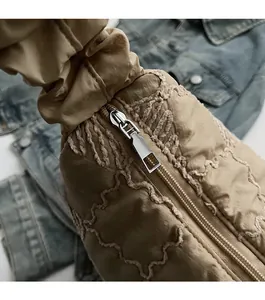 Close-up of smooth silver metal zipper on beige quilted fabric of a tote bag