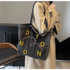 Detail of grey denim tote bag with yellow 3D embroidery and durable shoulder strap