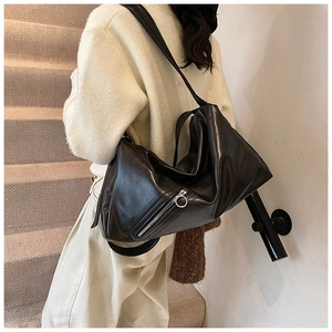 Close-up of minimalist black tote bag with silver ring zipper and soft leather texture