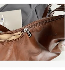 Detailed close-up of a smooth silver metal zipper on a brown leather tote bag with lining