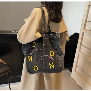 Detail of grey washed denim tote bag showing embroidery texture and side view on model