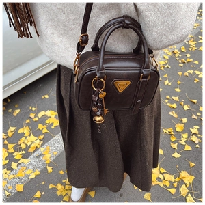 Detail der dunkelbraunen Vintage-Koffer-Tasche mit goldenem Logo und Herbst-Styling