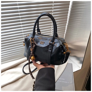 Detail of vintage black leather bowling bag featuring golden logo and metallic hardware