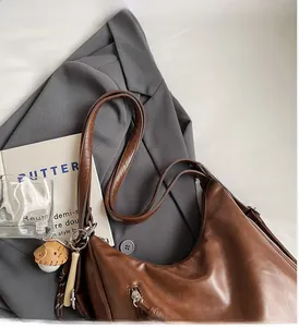 Brown faux leather shoulder bag detail with creative baseball bat and glove charm pendant