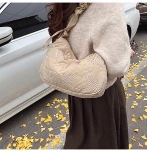 Detail of beige quilted shoulder bag with ruffled strap and chess grid embroidery