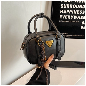 Detail einer schwarzen Boston-Tasche mit goldenen Beschlägen und geflochtenem Anhänger