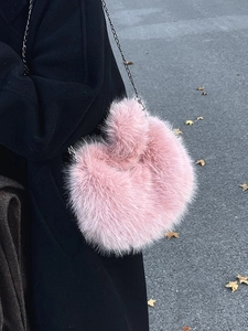 Borsa a tracolla in peluche rosa a forma di gnocco indossata su cappotto nero