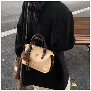 Detailed view of the contrast color handbag with golden hardware and plush ball charm