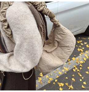 Detailed view of beige quilted tote bag with heart patterns and ruffled shoulder strap