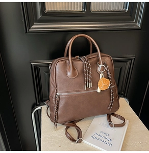 Dettaglio zaino vintage in pelle PU marrone con cerniera intrecciata e ciondolo