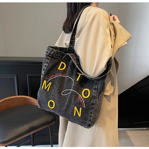 Detail of black denim tote bag with yellow letter embroidery and freedom slogan