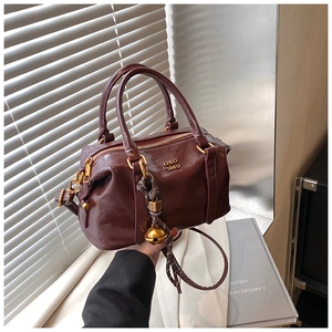 Detail of vintage burgundy bowling bag with glossy leather texture and gold logo