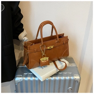 Detail of a brown leather briefcase with gold buckle on a silver suitcase