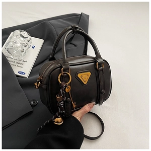 Detail der braunen Vintage-Umhängetasche aus Leder mit Metallplakette und Anhängern
