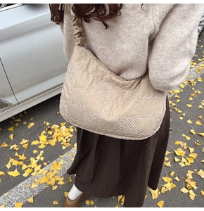 Close-up of beige quilted tote bag with wave embroidery and pleated shoulder strap