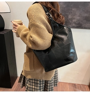 Grote zwarte geweven lederen tote bag met verstelbare schouderriem gedragen door model