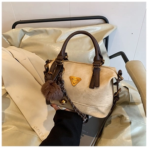 Close-up of apricot Boston bag with brown handles and gold triangle logo plate