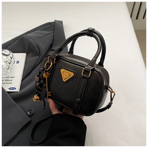 Detail der schwarzen matten Leder-Mini-Boston-Tasche mit goldenen Reißverschlüssen und Anhänger