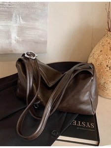 Deep coffee brown soft leather tote bag with silver floral hardware on black blazer