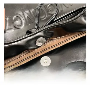Detail of silver magnetic closure and brown interior lining on black leather bag