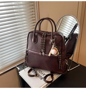 Dettaglio borsa in pelle marrone con ciondolo da baseball su riviste business