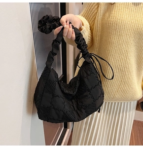 Close-up of black nylon pleated tote bag with scrunchie handle and drawstring detail