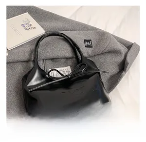 Detailed close-up of a black leather hobo bag with an embossed logo and a chic leather bow