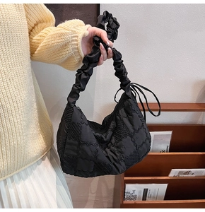 Detail of black puffer tote bag showing quilted square texture and ruched handle