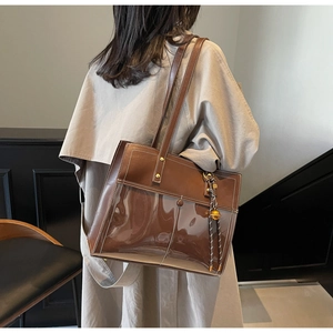 Detail view of large dark brown PU leather and PVC tote bag with stylish tassel charm