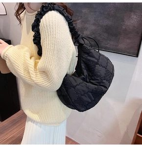 Close-up of pleated shoulder strap and quilted nylon fabric on black tote bag