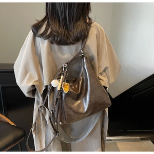 Deep brown oversized leather tote bag on model showing large capacity and baseball charms