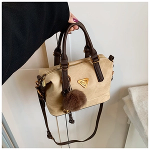 Close-up of beige suede Boston bag with brown handles and gold triangle logo charm