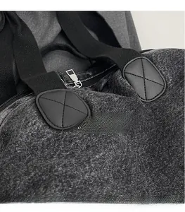 Macro detail of dark grey denim backpack showing cross-stitched leather patch and webbing
