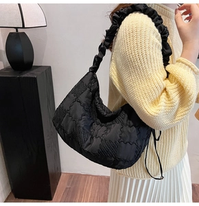 Close-up of quilted black nylon shoulder bag with ruffled strap on model