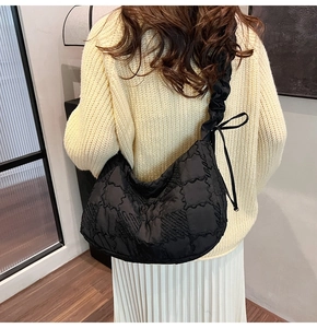 Detailed view of black quilted nylon tote bag with drawstring pleated shoulder strap details