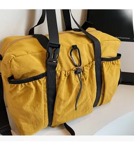 Detail of yellow nylon bucket bag showing black adjustable straps and D-ring clip