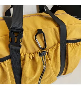 Close-up of bright yellow nylon tote bag featuring durable black straps and side pockets