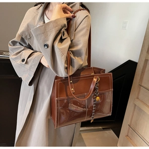 Detail of a brown tote bag featuring mixed textures and elegant white contrast stitching